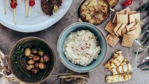 A variety of Mediterranean appetizers featuring hummus, olives, and grilled vegetables set on a rustic table.
